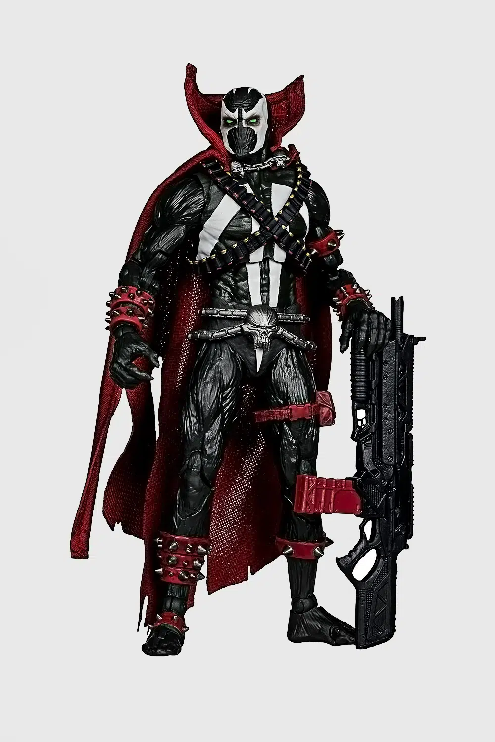 Action figure in black and white armor with a red cape, holding a futuristic gun in a combat-ready stance.